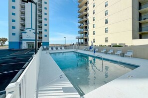 Una piscina con superficie de agua azul cristalina, rodeada por una terraza blanca y sillas de descanso.
