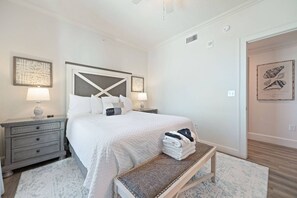 Ein Schlafzimmer mit Bett, Nachttischen, einer Bank und Kunstwerken an den Wänden.