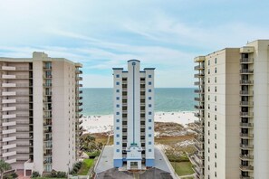 Ein Hochhaus-Hotel mit einem zentralen Turm, Blick auf den Strand und einem Sandstrand im Hintergrund.