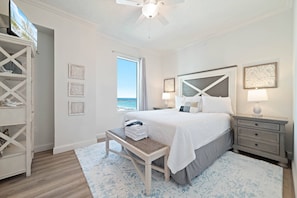 Ein Schlafzimmer mit einem Bett, Nachttischen, einer Bank, einem Deckenventilator und einem Fenster mit Blick.