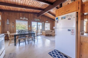 A wooden interior with a dining area, a refrigerator, and a view through the door. - Sun Byrne - S Nags Head MP 18, 200 Feet to the Beach, Ocean View, Flex Stays (Nags Head)