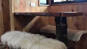 A wooden interior with a bench, a fluffy white cushion, and a window with a view.