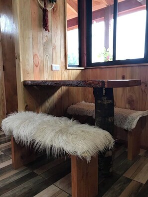 Un intérieur en bois avec un banc, un coussin moelleux blanc et une fenêtre donnant sur un paysage agréable.