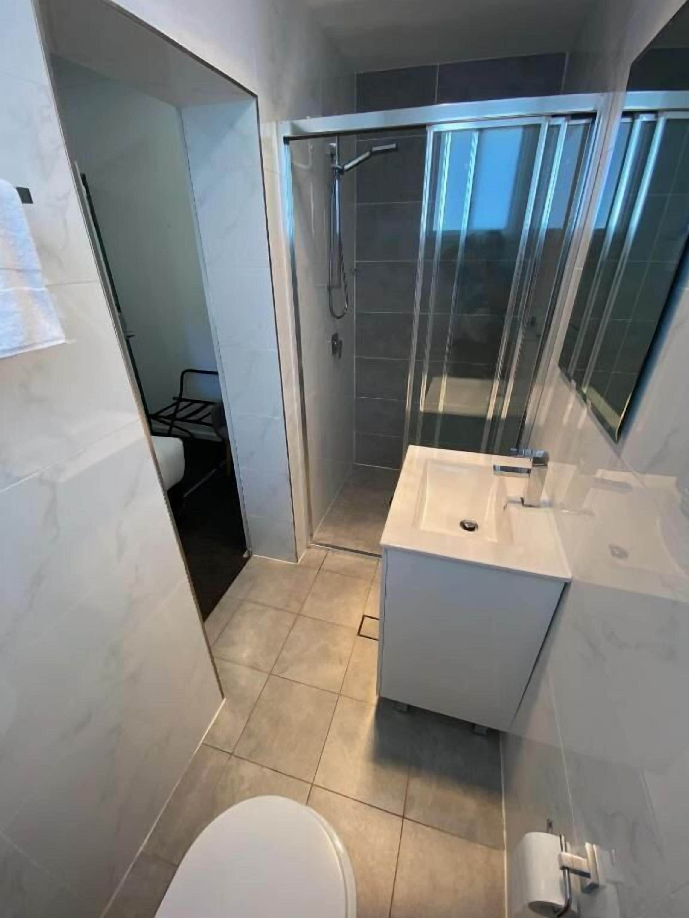 Deluxe driepersoonskamer | Badkamer | Een douche, gratis toiletartikelen, een haardroger, handdoeken