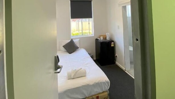 A room with a bed, a window, a door, and a small table. - Central Motel (Mudgee)