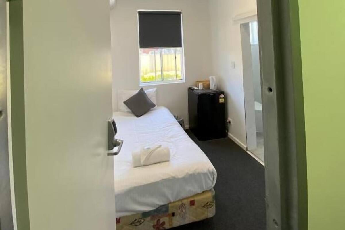 Une pièce avec un lit, une fenêtre, une porte et une petite table.