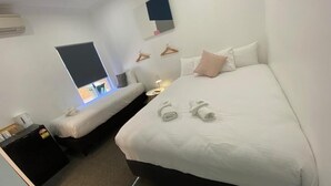 A hotel room with a large bed, a smaller bed, a desk with a lamp, and a TV on the wall. - Central Motel (Mudgee)