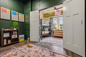 Habitación infantil con literas, una estantería y una puerta que da a otra habitación.