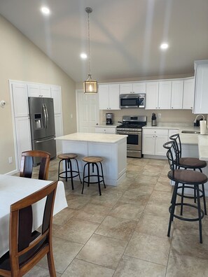 A modern kitchen with white cabinets, stainless steel appliances, and a central island with stools.