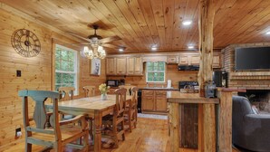 Interno di una baita di legno con zona pranzo, cucina e camino.