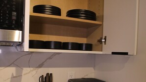 Eine Küche mit Mikrowelle, Backofen und einem Schrank mit schwarzen Behältern.