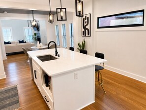 A modern kitchen with a white island, black faucet, pendant lights, and a large window. -     Stylish Retreat Near Downtown (Atlanta)