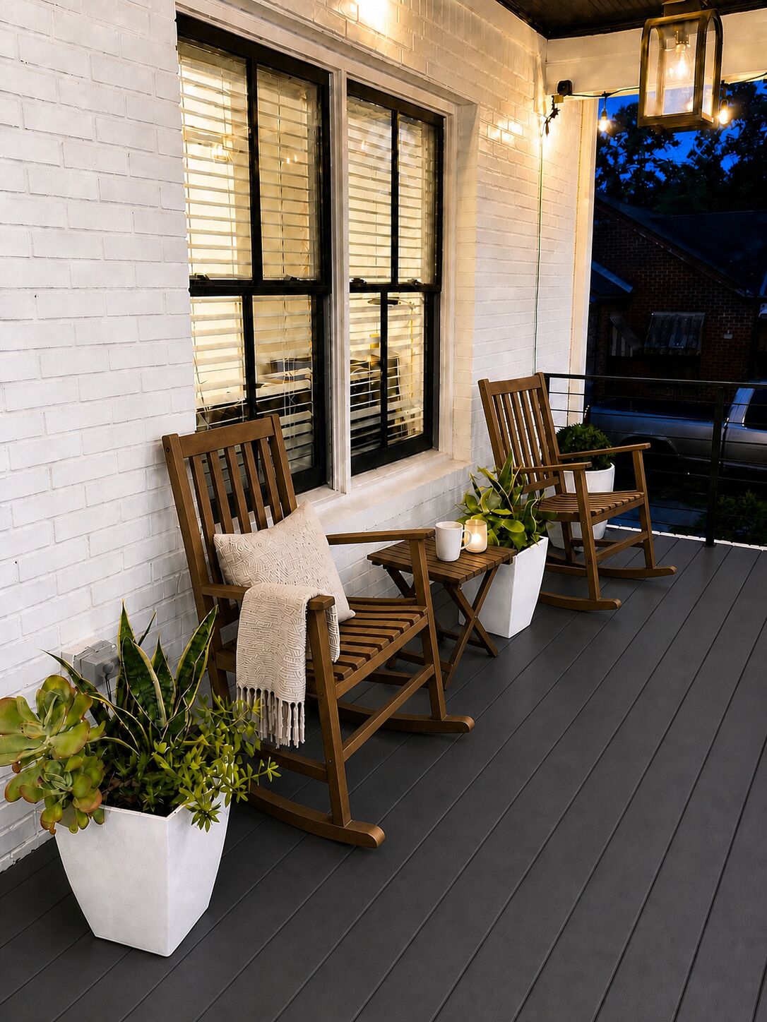 A porch with two rocking chairs, a table, and potted plants.