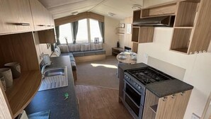 Cuina compacta d'una caravana, amb fogó, forn i zona de menjador amb taula i cadires.
