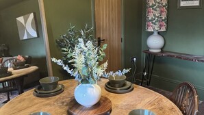 Ein Esstisch mit Blumen in einer Vase, umgeben von Stühlen und Schalen.