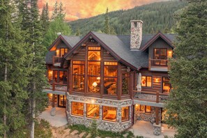 A log cabin with multiple large windows, a stone foundation, and a balcony. - NEW LISTING! Luxury log home, nearby shuttle, hot tub, game tables, several sound systems, views!! (Breckenridge)