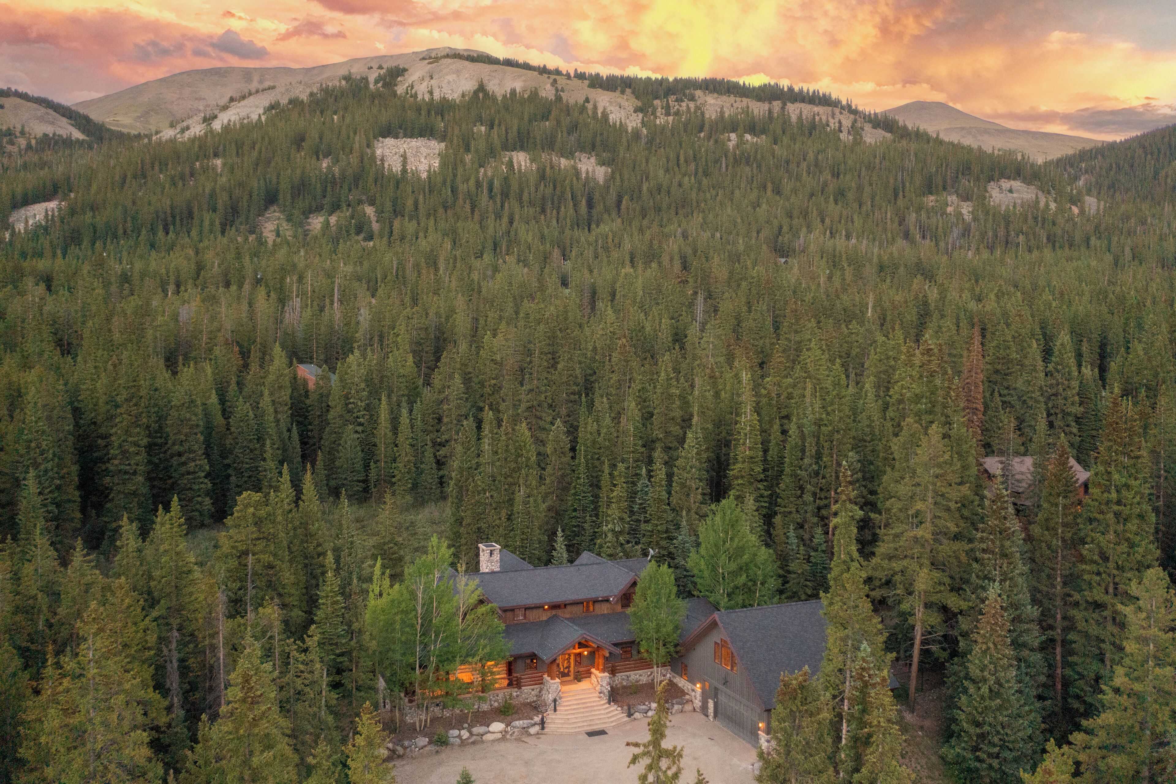 Eine Lodge, umgeben von dichtem Wald, mit einer Bergkulisse im Hintergrund.