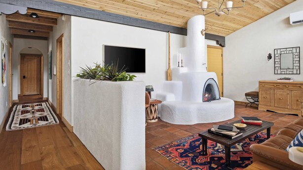 Een moderne woonkamer met een open haard, houten plafond en een aan de muur bevestigde televisie.