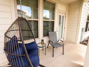 A porch with a hanging chair, a table with a candle, and a chair. - Modern Comfort in the Heart of Southside (Jacksonville)