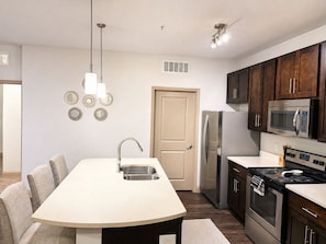 Una cucina moderna con isola centrale, elettrodomestici in acciaio inossidabile e pensili in legno scuro.