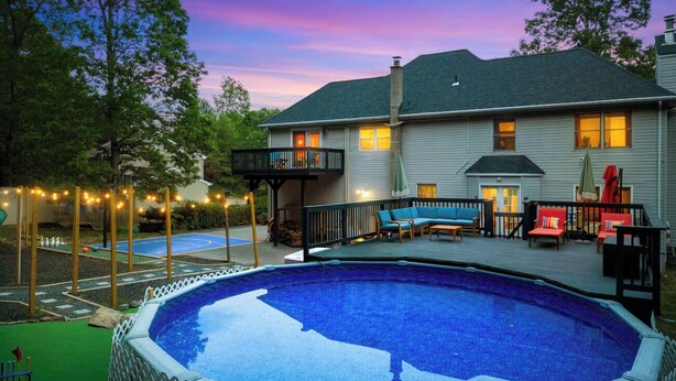 A swimming pool with a deck, a covered patio area, and a house in the background. - Heated Pool, Mini Golf, Bowling, Hot Tub, GameRoom (East Stroudsburg)