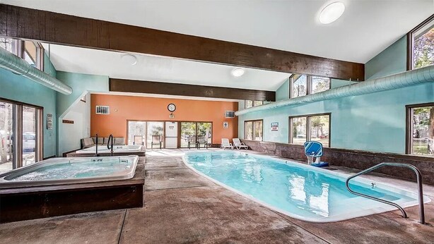 Et poolområde med jacuzzi, liggestole og frit udsyn til omgivelserne.