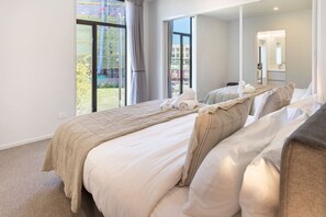 A bedroom with a large bed, a mirror, and a view of the outside. - Spacious CBD Townhouse | Stadium + Parking (Christchurch)