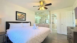 A bedroom with a bed, a ceiling fan, a nightstand, a dresser, a framed picture, and a large mirror. - Spacious 2BR Getaway in Myrtle Beach, Tennis, Pool (Myrtle Beach)