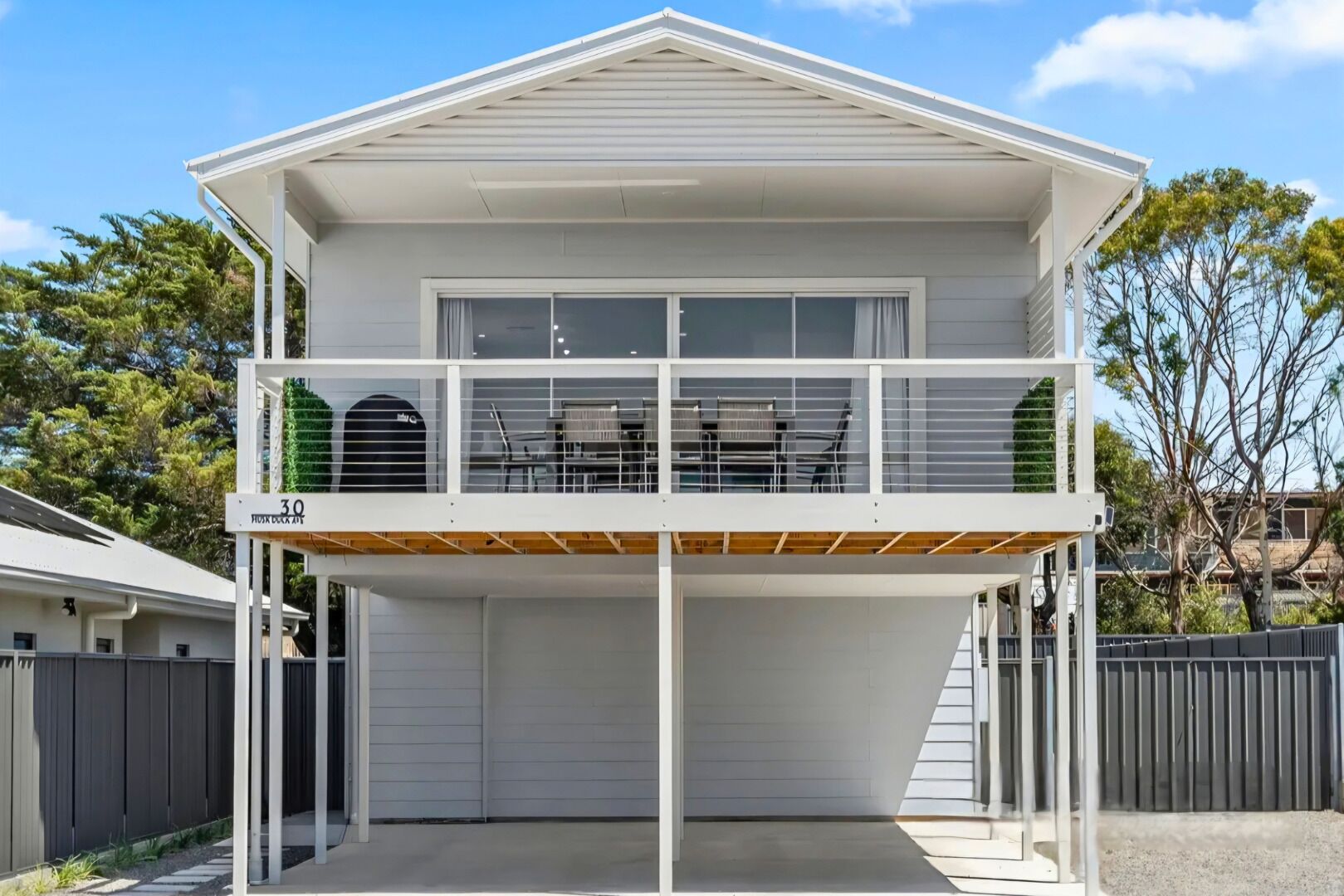Een tweelaags huis met een balkon, een garage en een omheinde tuin.