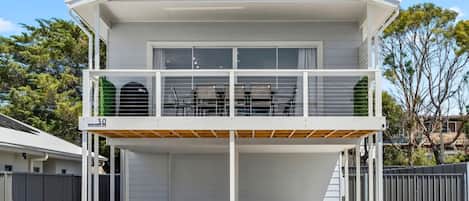 A two-story house with a balcony, a garage, and a fenced yard.