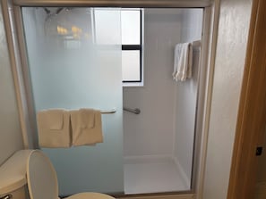 Kylpyhuoneessa on lasiseinäinen suihkukaappi, wc ja pyyheteline, jossa on kaksi pyyhettä.