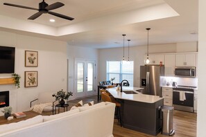 A modern kitchen with stainless steel appliances, a dining area with a sofa and chairs, and a ceiling fan. - Ocean Pearl Three Bedrooms (Pensacola)