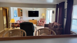 A living room with a television, a ceiling fan, a sofa, a chair, and a lamp. - Room 16-Three Bedroom Oceanfront w/balcony (Daytona Beach)