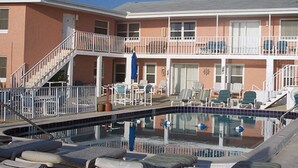 A hotel with a pool, outdoor seating, and a staircase leading to the upper floor. - 14-B One bedroom/one bath w/kitchen & living (Daytona Beach)