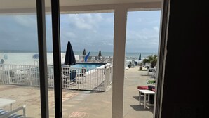 A pool area with lounge chairs and umbrellas, a view of the ocean, and a 'Welcome' sign. - Room 17-3/2 Ocean Front-1st Floor (Daytona Beach)