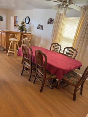 Ein Essbereich mit einem Holztisch, vier Stühlen, einer Bar und einem Deckenventilator.
