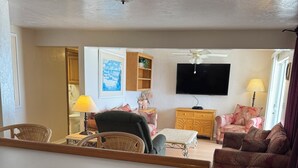 A living room with a television, a ceiling fan, a wooden cabinet, and a patterned sofa. - Room 17-3/2 Ocean Front-1st Floor (Daytona Beach)