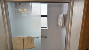 Ein Badezimmer mit Duschkabine, Toilette und Handtuchhalter mit zwei Handtüchern.