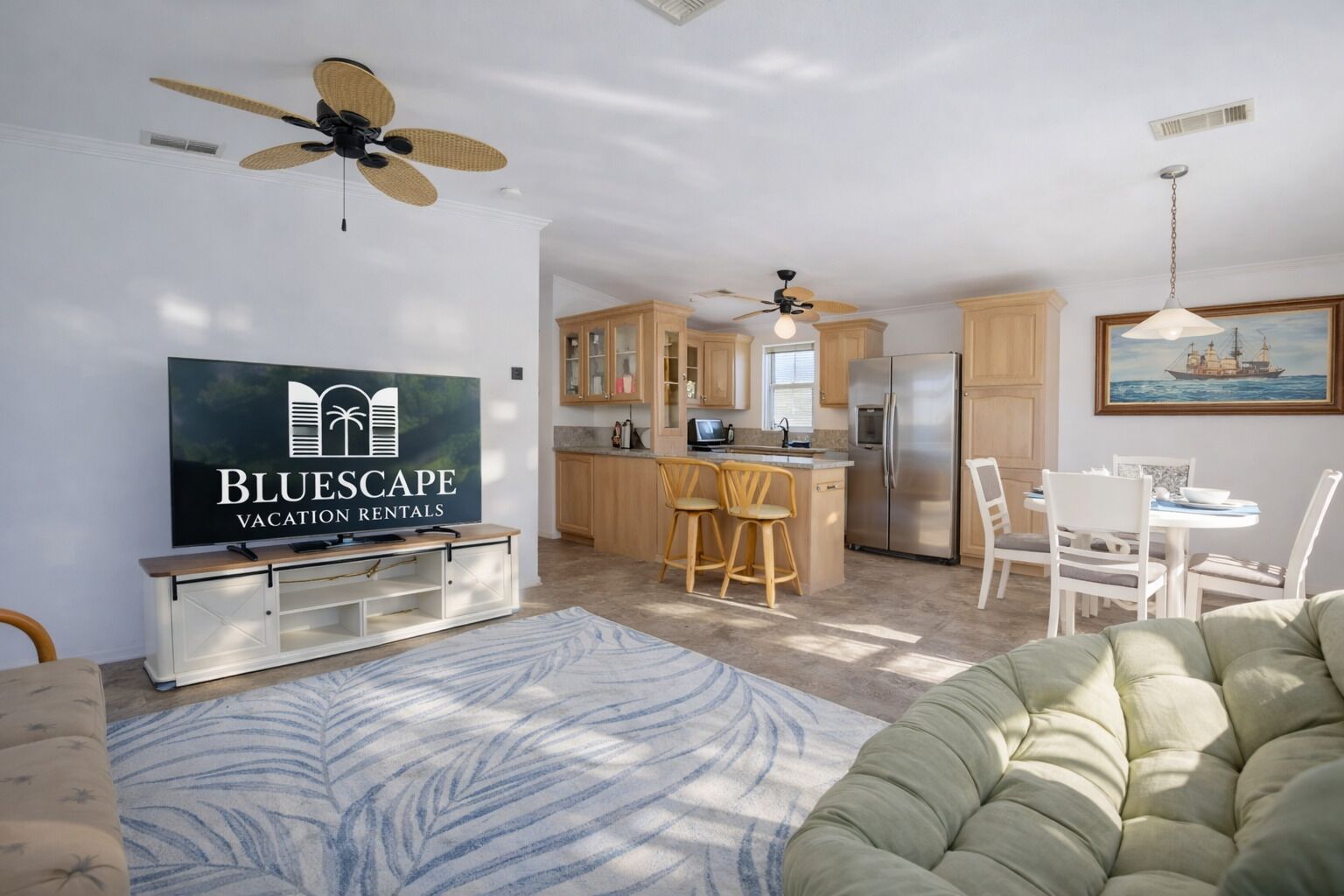 A modern kitchen with wooden cabinets, a central island, and a dining area with white chairs.