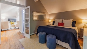 Ein Schlafzimmer mit einem großen Bett, einem Spiegel, einem Schreibtisch und einem Sessel.