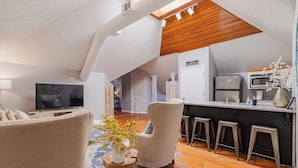 Ein moderner Loft-Wohnraum mit Küche, Essbereich und Fernseher.