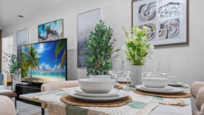 Un coin repas avec une table dressée pour quatre personnes, entourée de canapés.