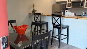 A modern kitchen with white cabinets, a microwave, and a dining area with black chairs and a glass table.