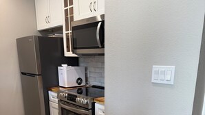 A kitchen with white cabinets, a stainless steel refrigerator, a microwave, a built-in oven, and a dishwasher.