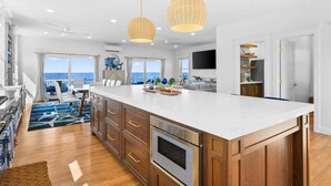 A spacious kitchen with a large island, wooden cabinets, and a built-in oven. - Beachfront Bliss with Marsh Views & Private Dock (East Sandwich)