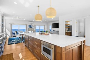 A spacious kitchen with a large island, wooden cabinets, and a built-in oven. - Beachfront Bliss with Marsh Views & Private Dock (East Sandwich)