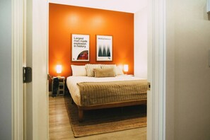 A bedroom with a bed, two wall-mounted lamps, and two framed pictures.