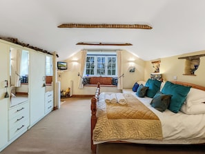 Un dormitorio con cama, cómoda, ventana con cortinas, televisor y estante en la pared.