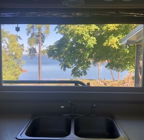 A kitchen with a window view of a lake and trees. - Lakehouse Retreat with dock, paddle boat, hot tub, canoe & kayaks! Lake Hartwell (Anderson)