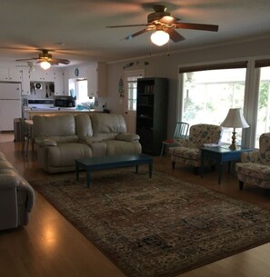 A living room with a sofa, a coffee table, patterned chairs, a rug, and ceiling fans. - Lakehouse Retreat with dock, paddle boat, hot tub, canoe & kayaks! Lake Hartwell (Anderson)